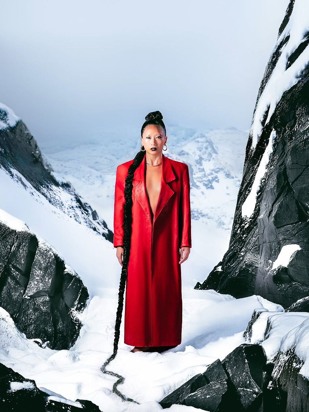 Mannequin en manteau rouge long dans un paysage de neige et de rochers