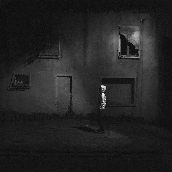 Cover 1001FT : un homme devant une maison en ruines, de nuit, en noir et blanc